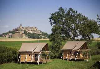 Dos cabañas en un campo verde con vistas al pueblo medieval de Cordes-sur-Ciel en Occitania, Francia.