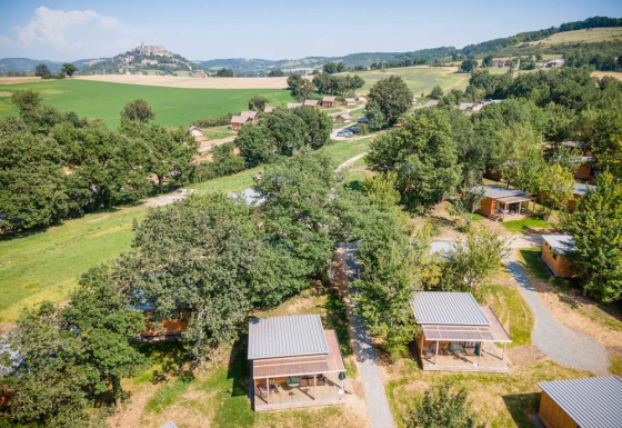 Luftfoto af træhytter i det grønne landskab ved Huttopia Pays de Cordes sur Ciel, Occitanie, Frankrig.