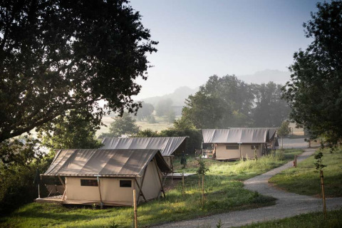 Vista de tiendas de glamping entre la vegetación en Huttopia Pays de Cordes sur Ciel, Occitania, Francia.