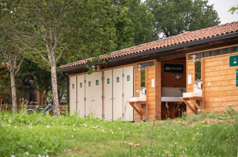 Edificio sanitario y estación de lavado de platos en Huttopia Pays de Cordes sur Ciel, Occitanie, Francia.
