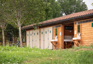 Bâtiment sanitaire et espace vaisselle au Huttopia Pays de Cordes sur Ciel, parc de vacances en Occitanie, France.