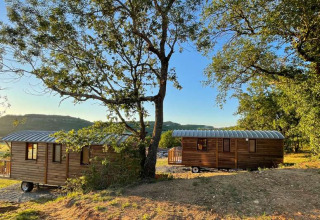 To træhytter i Huttopia Pays de Cordes sur Ciel, omgivet af natur og skov i Occitanie, Frankrig.