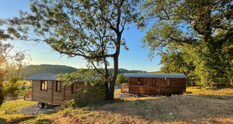 Twee houten hutten bij Huttopia Pays de Cordes sur Ciel, omringd door natuur in Occitanie, Frankrijk.