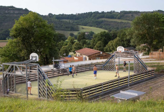 Børn spiller på en multifunktionssportsbane i det naturskønne Huttopia Pays de Cordes sur Ciel, Frankrig.