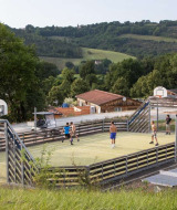 Niños jugando en una cancha multideportiva en Huttopia Pays de Cordes sur Ciel, Occitanie, Francia.