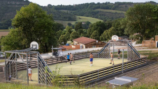 Niños jugando en una cancha multideportiva en Huttopia Pays de Cordes sur Ciel, Occitanie, Francia.