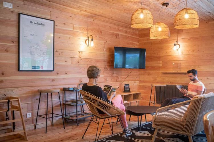 Gezellige loungehoek met houten wanden en moderne meubels bij Huttopia Pays de Cordes sur Ciel, Frankrijk.