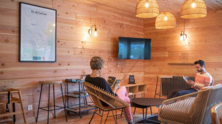 Acogedora zona de descanso con paredes de madera y muebles modernos en Huttopia Pays de Cordes sur Ciel, Francia.