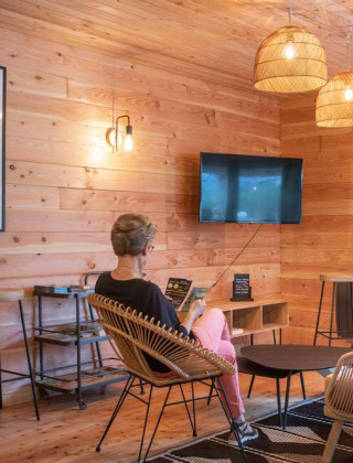 Acogedora zona de descanso con paredes de madera y muebles modernos en Huttopia Pays de Cordes sur Ciel, Francia.