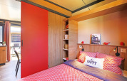 Knusse slaapkamer in Chalet Evasion Vista met rode tinten, houtaccenten en natuurlijk licht.
