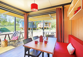 Interiør af Chalet Evasion Vista-hytte med rød indretning, spisebord og udsigt til flere små hytter udenfor.
