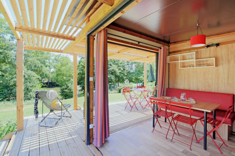 Chalet Evasion Vista: Gezellige chalet met rood eetgedeelte, open terras en zicht op groene omgeving.