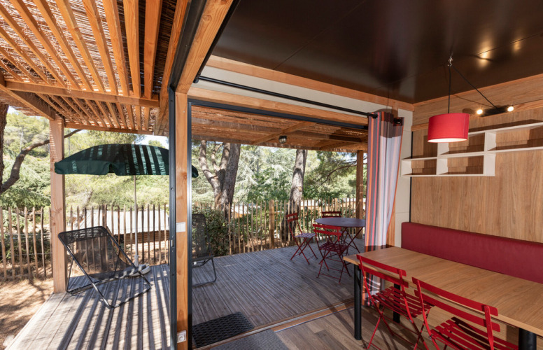 Uitzicht vanuit Chalet Evasion Vista met open houten dek, zitgelegenheid buiten en bosrijke omgeving.