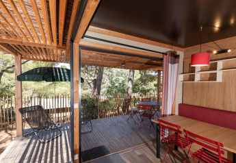 Vista desde la cabaña Chalet Evasion Vista con terraza de madera, asientos exteriores y entorno boscoso.
