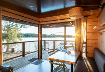 Solopgang set fra en hyggelig træhytte Chalet Evasion Vista med udsigt til sø og træer gennem store vinduer.