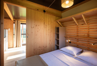 Dormitorio luminoso de madera con cama doble en el Chalet Evasion Vista de Huttopia De Roos, Países Bajos.