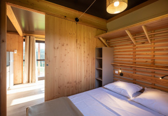 Dormitorio luminoso de madera con cama doble en el Chalet Evasion Vista de Huttopia De Roos, Países Bajos.