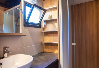 Moderne badeværelse i Chalet Evasion Vista med vask, bruser, hylder og åbent vindue med trædetaljer.