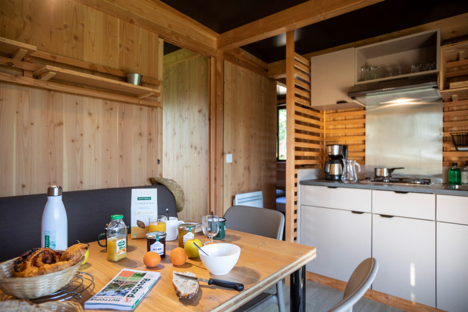 Moderne keuken en eetruimte in Chalet Evasion Vista met ontbijt op een houten tafel en houtinterieur.