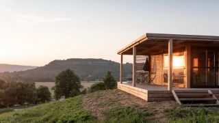 Solnedgang ved Chalet Evasion Vista, en træhytte med veranda og panoramaudsigt over det bakkede landskab.