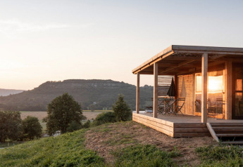 Zonsondergang aan Chalet Evasion Vista, een houten chalet met terras en zicht op glooiende heuvels en natuur.