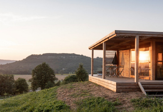 Zonsondergang aan Chalet Evasion Vista, een houten chalet met terras en zicht op glooiende heuvels en natuur.
