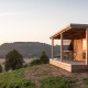 Solnedgang ved Chalet Evasion Vista, en træhytte med veranda og panoramaudsigt over det bakkede landskab.