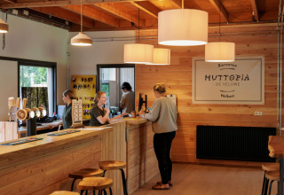Reception area at Camping Huttopia De Veluwe in Gelderland, Netherlands, with wood décor and welcoming staff.