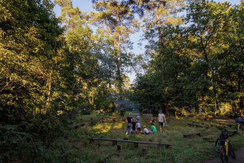 Familias reunidas alrededor de una fogata en Camping Huttopia De Veluwe, parque vacacional en Gelderland, Países Bajos.