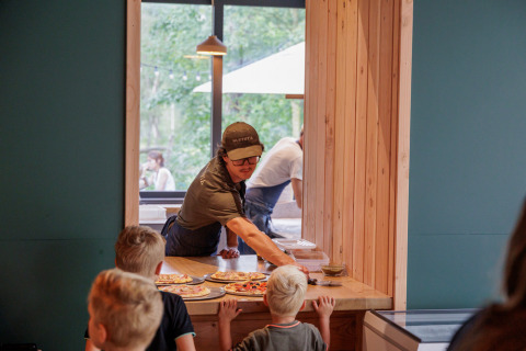 Niños esperan pizza servida por un empleado en el Camping Huttopia De Veluwe en Gelderland, Países Bajos.