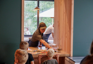 Kinderen wachten op geserveerde pizza bij het Huttopia De Veluwe vakantiepark in Gelderland, Nederland.