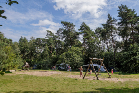Niños jugando en el parque infantil en Camping Huttopia De Veluwe, parque vacacional en Gelderland, Países Bajos.