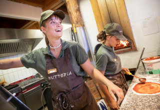 Twee enthousiaste medewerkers maken pizza in de keuken van Camping Huttopia De Veluwe in Gelderland.