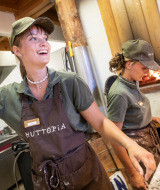 Zwei fröhliche Mitarbeiter bereiten Pizza zu in der Küche von Camping Huttopia De Veluwe, Gelderland.
