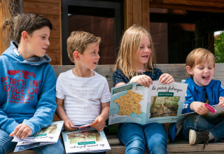 Kinderen zitten op een bank bij Camping Huttopia De Veluwe in Gelderland, Nederland, en lezen boekjes.