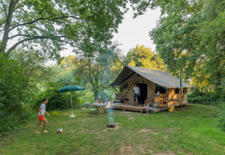 Gezin beleeft kampeerplezier bij een tent tussen het groen op Huttopia De Veluwe, Gelderland.