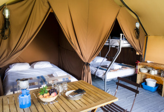 Interior de una tienda safari Canadienne Cosy en Camping Huttopia De Veluwe, Países Bajos, con camas y mesa.