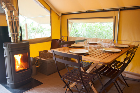 Interieur van een Canadienne Cosy safaritent op Camping Huttopia De Veluwe met houtkachel en tafel.