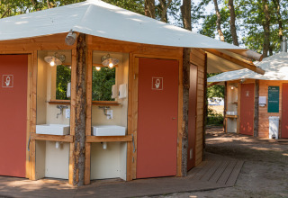 Moderne campingtoiletten en wasbakken bij Huttopia De Roos vakantiepark in Overijssel, Nederland, te midden van groen.