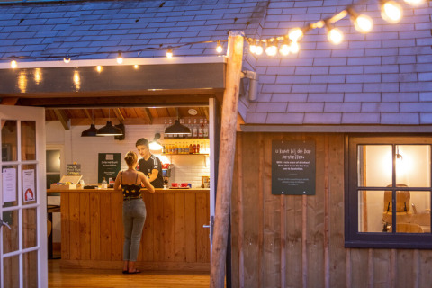 Luces de tarde en el bar de Huttopia De Roos, un parque de vacaciones en Overijssel, Países Bajos, con dos personas.