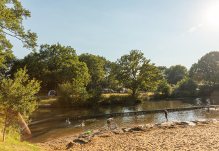 Bambini che giocano sulla spiaggia fluviale al parco vacanze Huttopia De Roos, Overijssel, Paesi Bassi, al sole.
