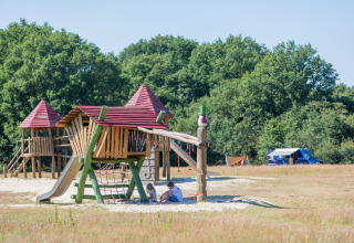Legeplads med børn under rutsjebane ved ferieparken Huttopia De Roos i Overijssel, Holland, omgivet af natur.
