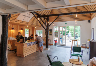 Die Rezeption des Ferienparks Huttopia De Roos in Overijssel, Niederlande, mit Holzdekor und Gästen.