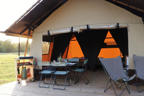 Tienda safari Classic Wood en Huttopia De Roos, Países Bajos, con zona de comedor exterior y barbacoa.
