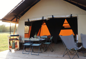 Tenda safari Classic Wood all'Huttopia De Roos nei Paesi Bassi con zona pranzo all'aperto e barbecue.