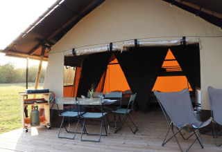 Tienda safari Classic Wood en Huttopia De Roos, Países Bajos, con zona de comedor exterior y barbacoa.
