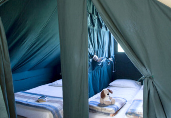 Binnenkant van een Cahutte-safaritent bij Huttopia De Roos, Nederland, met bedden en speelgoed.