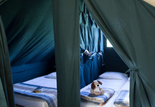 Interior de una tienda safari Cahutte en Huttopia De Roos, Países Bajos, con camas y juguetes.