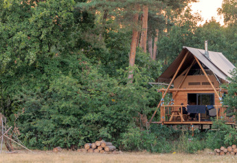 Safaritent Cahutte verscholen in het bos bij Huttopia De Roos, Nederland, omgeven door groen.
