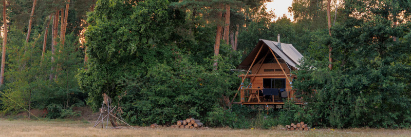Tienda safari Cahutte en el bosque de Huttopia De Roos, Países Bajos, rodeada de vegetación.